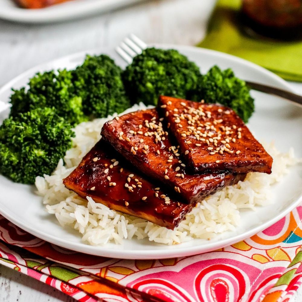 Slices on teriyaki tofu on a bed of rice and broccoli.