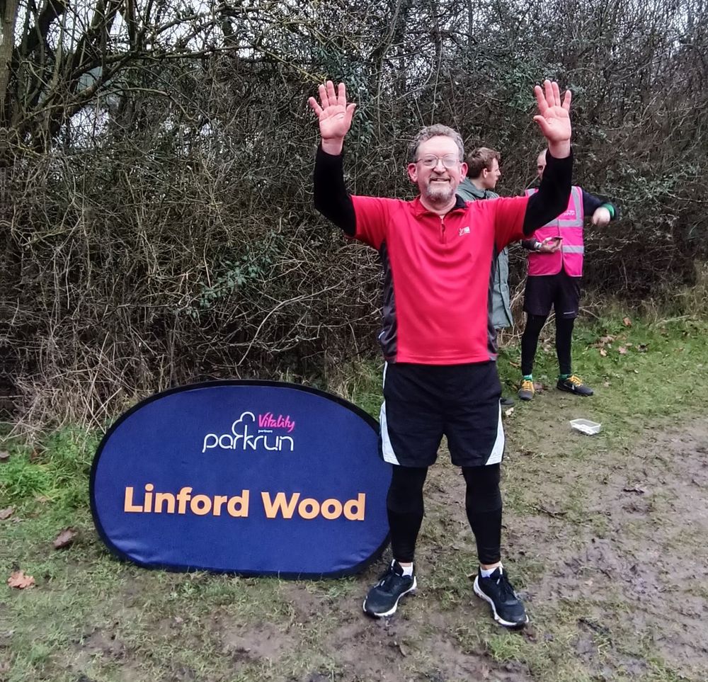 Man at Parkrun next to sign 
