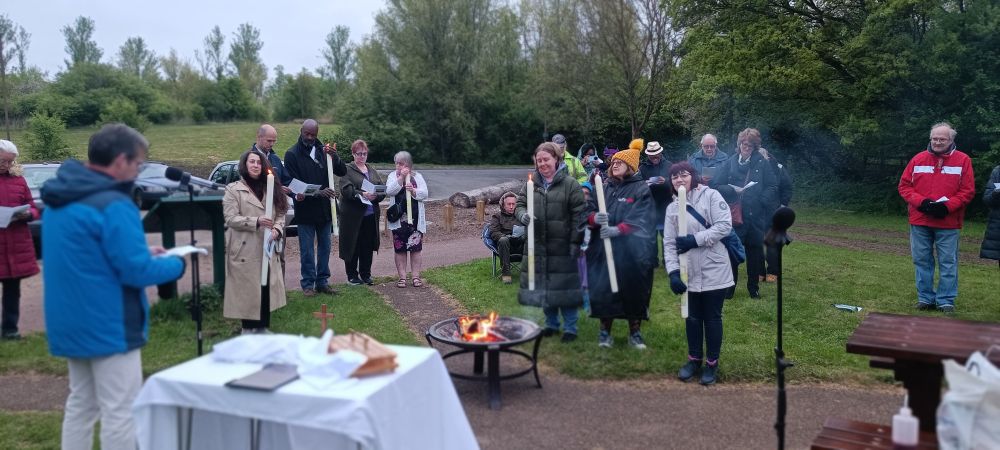 Easter candles being lit at an outdoor communion service