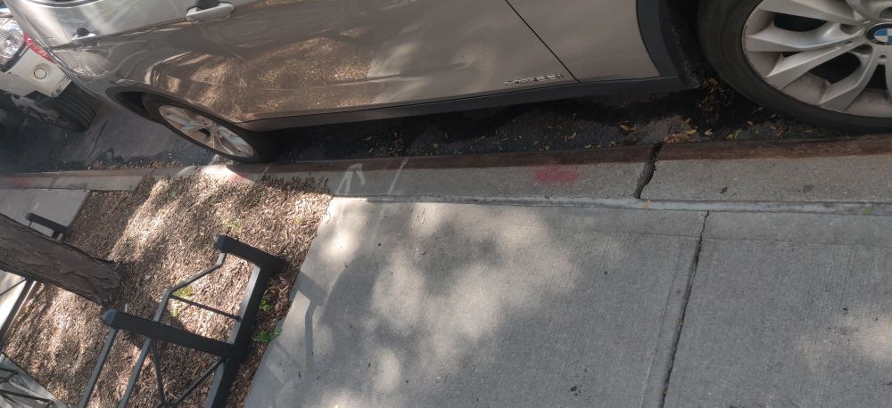 picture of a car parallel parked with no visible space between its wheels and the curb