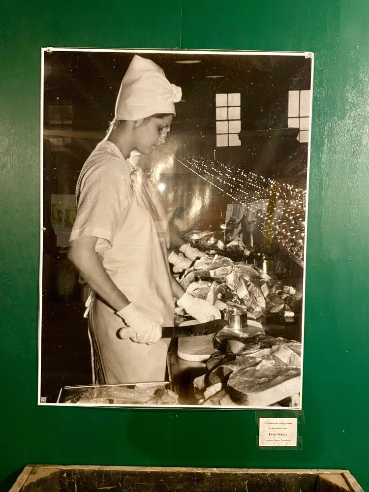 An old photo of a woman chopping fish with a large knife