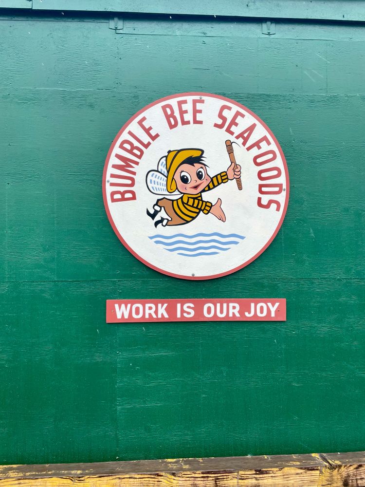 A logo for Bumble Bee Seafood with a sign that says “work is our joy”