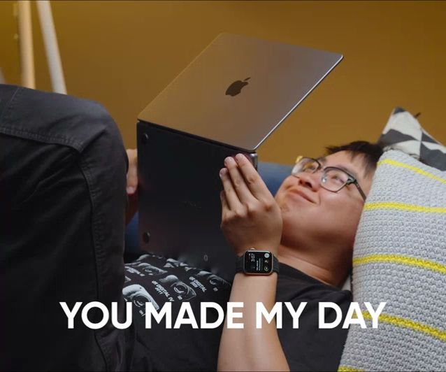 a man is laying on a couch using an apple laptop