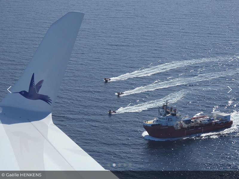 Image montrant une partie de l'avion "Le Colibri" et son sigle volant au dessus de navires de recherche en Méditerranée ( source https://www.pilotes-volontaires.org)