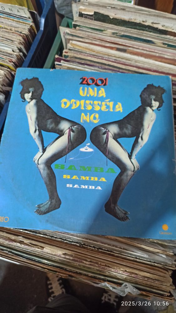 A imagem mostra uma capa de LP azul escrito 2001 uma odisseia no samba com uma imagem de mulher dançando espelhada e um disco voador