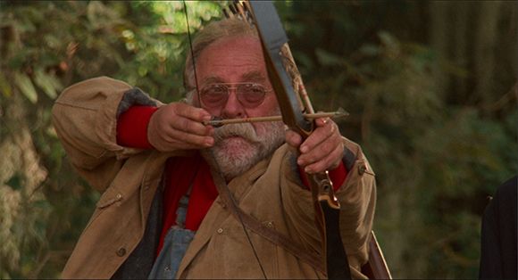 wilford brimley in Hard Target aiming a bow and arrow