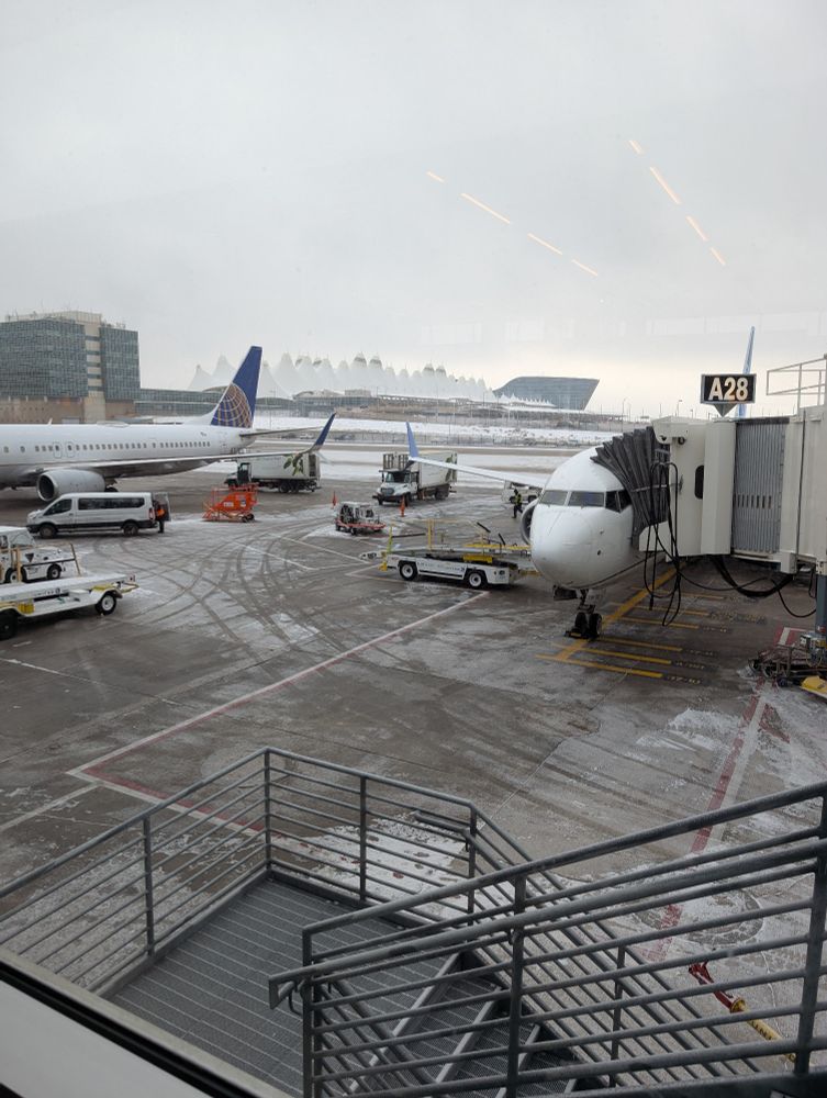 Photo looking from A gates at Denver International Airport towards the main terminal on a snowy day with two United aircraft at gates 