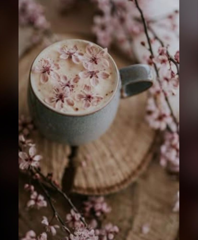 Coffee with sweet pink flowers in it sitting on a cut wood circle