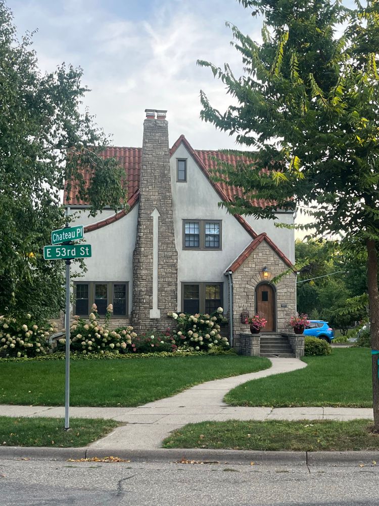 House with a brick chimney that has an stucco inlay arrow pointing up