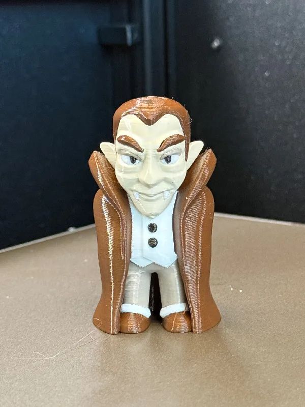 Photo of a 3D printed mini vampire in a white, tan, and brown Count Chocula color scheme.