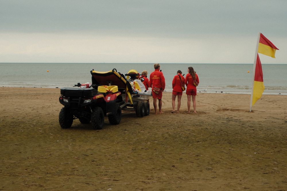 Lifeguards, a Jetski and a flag standing at the beach. 