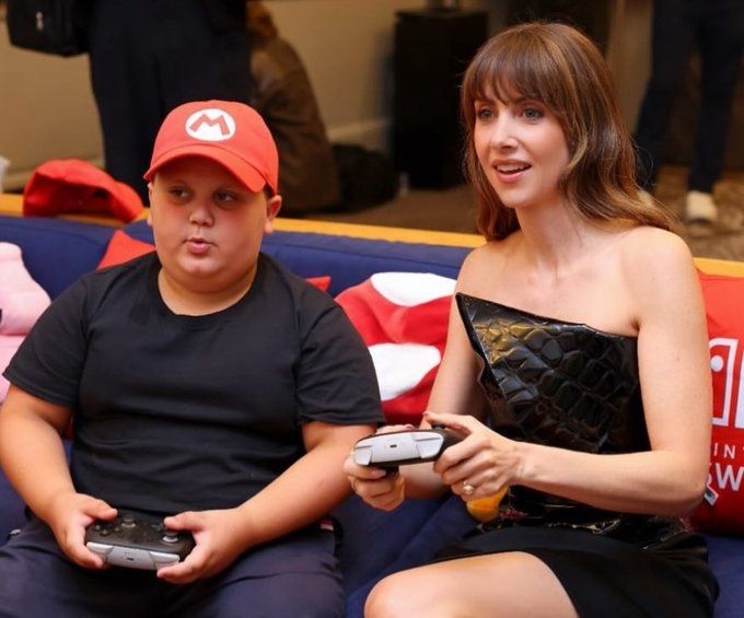 The rizzler in a Mario hat playing a video game with Alison Brie. Reality is collapsing around us and we are powerless to stop it.