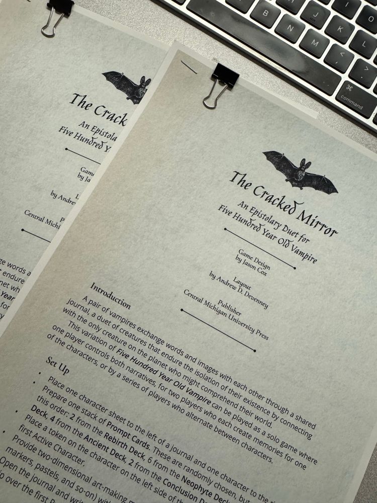 Picture of two printed copies of the rules for “The Cracked Mirror: An Epistolary Duet for Five Hundred Year Old Vampire”