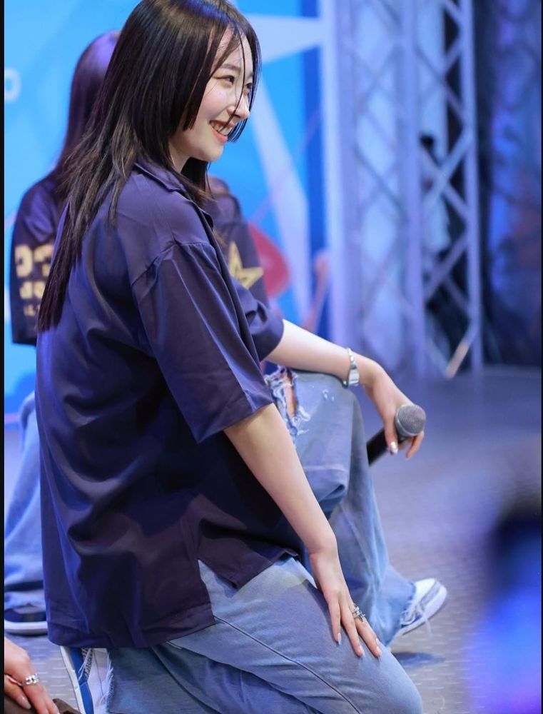 Nine from Kandis mid performance, in light blue jeans and an oversized blue shirt. She's smiling her gummy smile :))