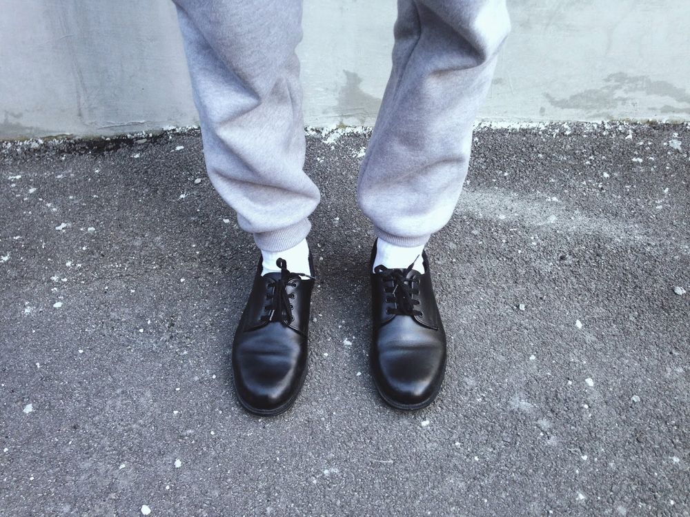 Grey tracksuit pants, white socks and shiny black school shoes.