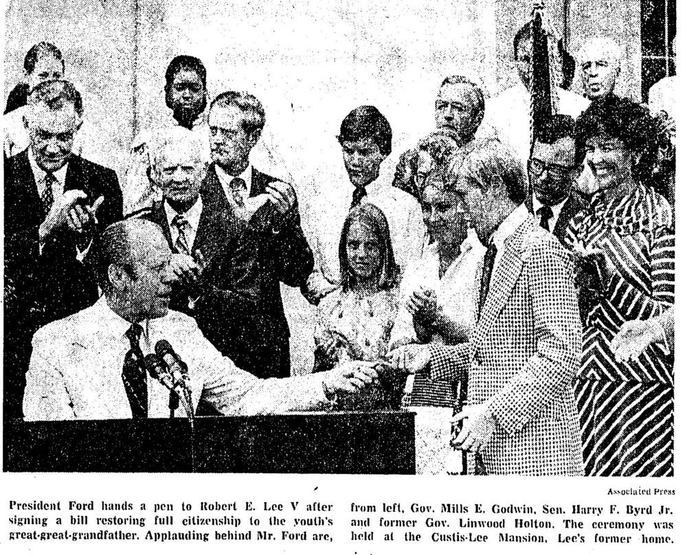 An Associated Press photograph shows President Gerald Ford handing a pen to Robert E. Lee V after signing a bill restoring full citizenship to the youth's great-great-grandfather. Behind them, a line of white observers applaud, while in the background an unidentified Black woman looks on from the porch.