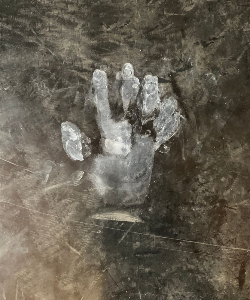 Valkoinen kämmenenjälki kuntosalin mustalla lattialla. 