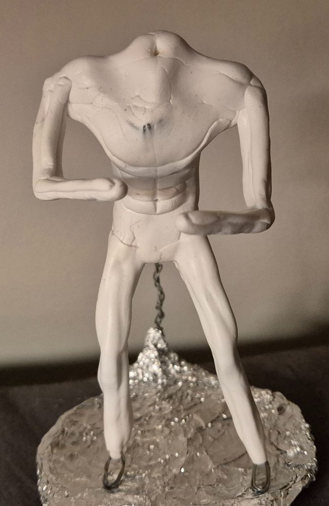 Muscular clay figure body with no feet, hands or head yet standing on tinfoil