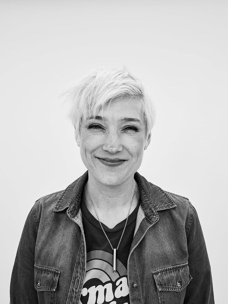 A woman with short blonde hair smiles for the camera in a black-and-white image.