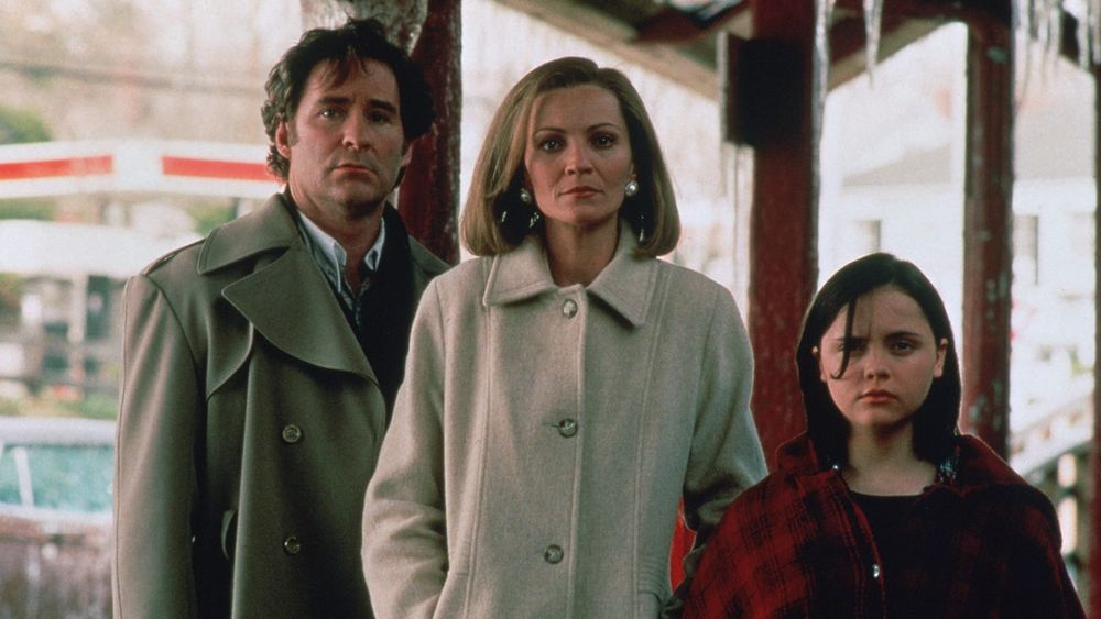 A man, a woman and a girl, all dressed for November weather, stand on a train platform with looks of deep concern.