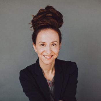 A woman smiles at the camera. Her hair is piled atop her head.