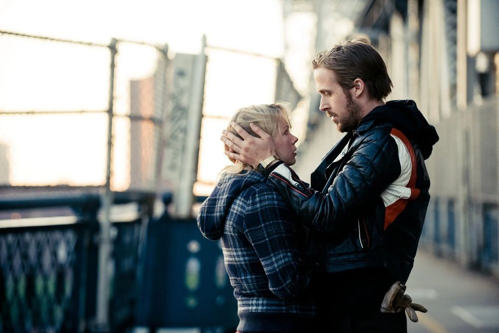Standing in profile, dressed for chilly weather, a young man and a young woman stare meaningfully into one another's eyes.