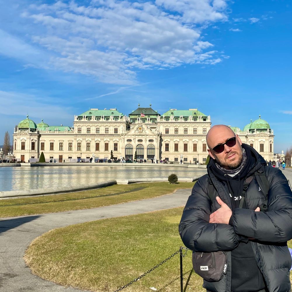 Photo of a tourist posing in the sun in front of Belvedere in Vienna