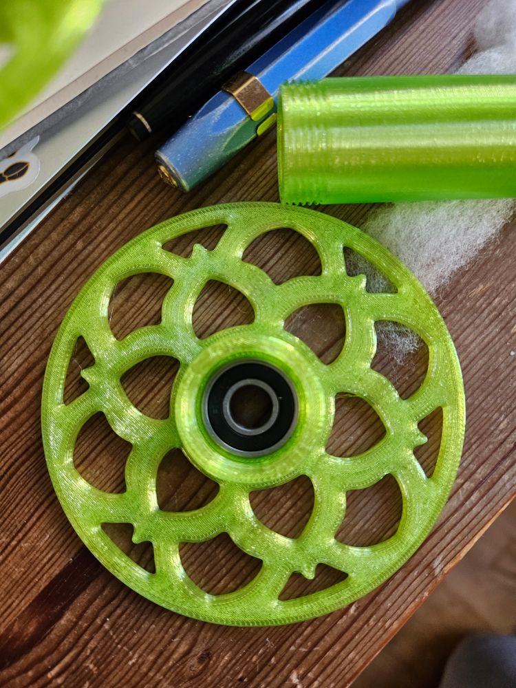 A close up showing the design of this 3D printed bobbin. All photos show different angles of my new neon lime green 3D printed bobbin for my EEW 6.0 spinning wheel. the last photo shows it installed on my electric spinning wheel.