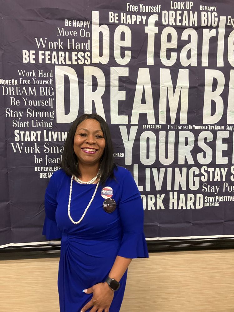 E smiling in front of a poster that reads DREAM