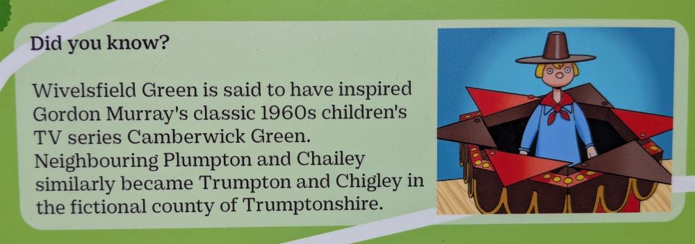 A photo of a sign with a drawing of Windy Miller from the children TV program Camberwick Green
The sign reads 
"Wivelsfield Green is said to have inspired Gordon Murray's classic 1960s childrens series Camberwick Green. Neighbouring Plumpton and Chailey similarly became Trumpton and Chigley in the fictional county of Trumptonshire"
