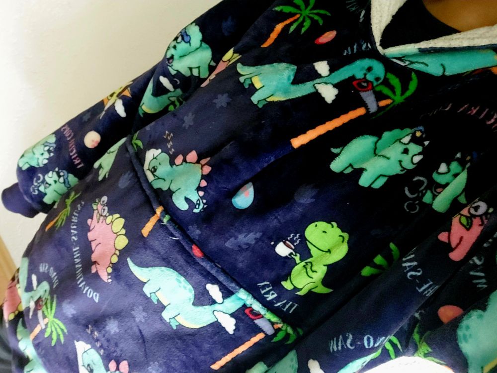 Ich stehend im dunkelblauen Oodie mit lustigen Dino-Motiven
