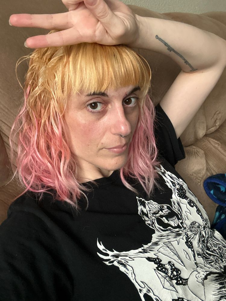 Corrin taking a selfie of her newly cut and bleached hair with light pink ends