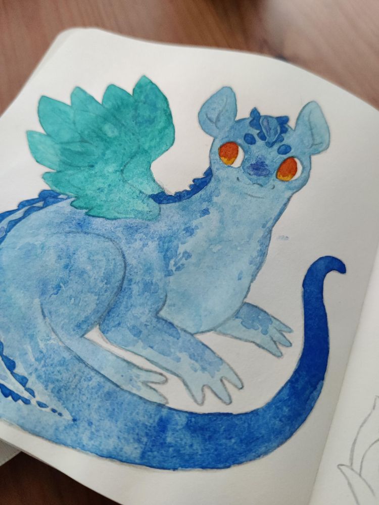 Close up of a sketchbook page with a drawing of a dragon coloured in blue and teal. The line art is not finished yet so it looks messy.