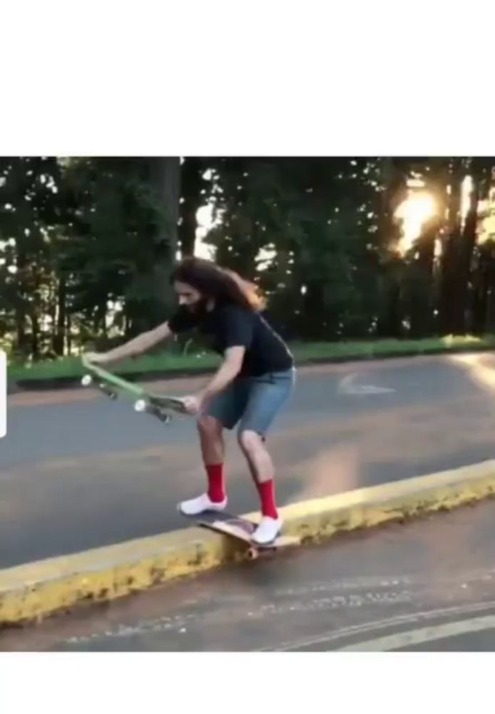 a man with long hair is riding a skateboard down a street