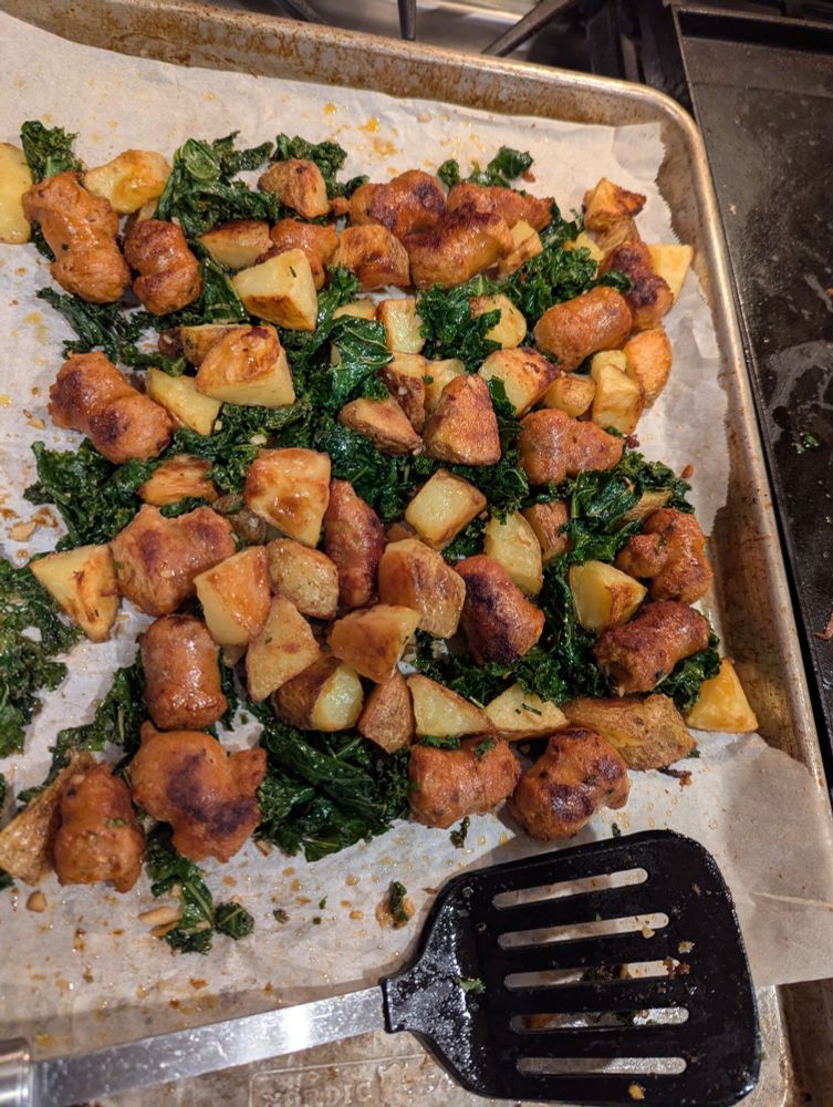 Sheet pan with browned potatoes and sausage tossed with sauteed kale 