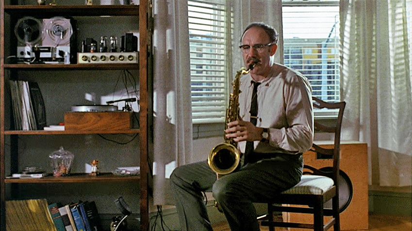 Gene Hackman sitting on a chair practicing the saxophone in the film, The Conversation. 