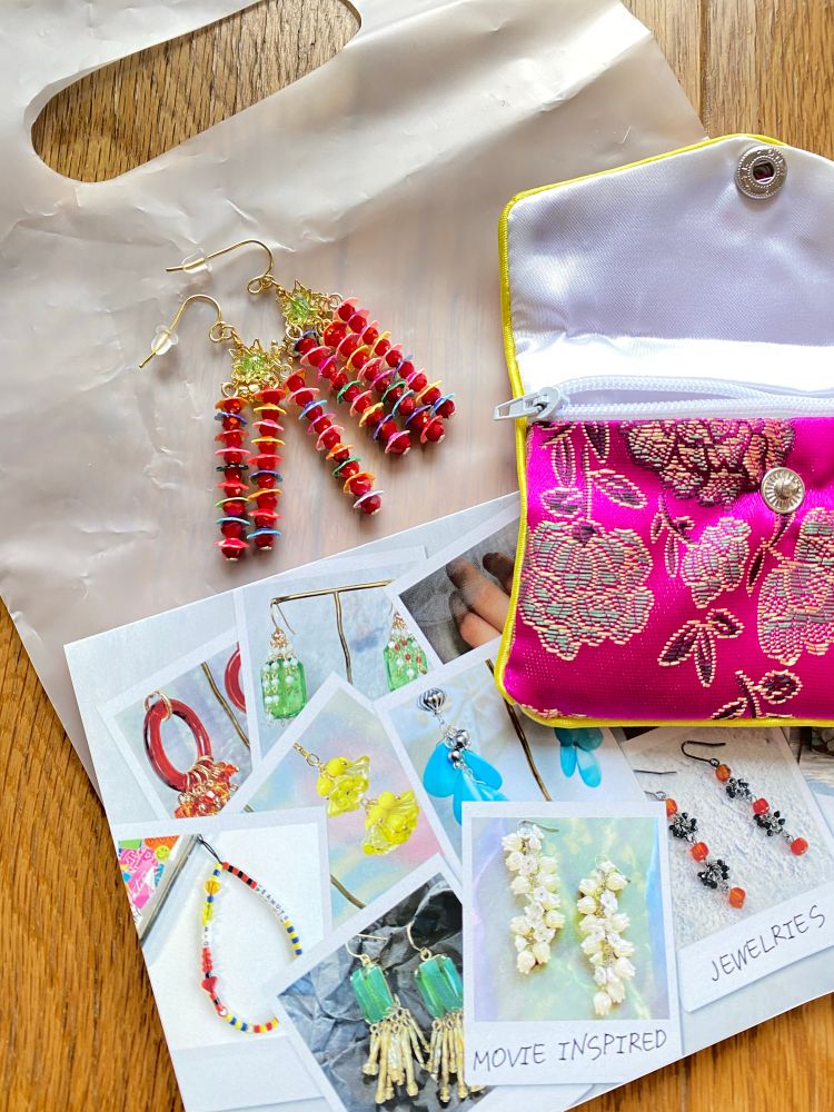 LIVERPOOL SUNSETさん制作の映画モチーフのピアス。赤やピンクなどの飾りが連なっている。