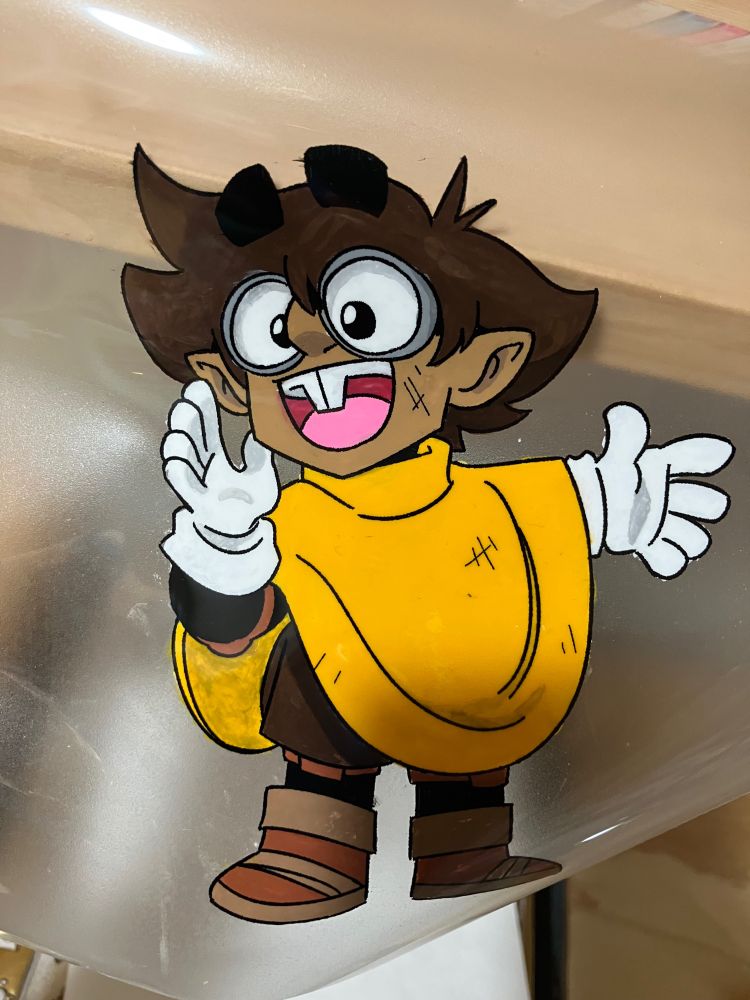 My first test of the cels using Noname, a gnome with big hair and goggles gesturing at something, on an inkjet transparency sheet. The paint is a lot messier and not framed, since I was getting used to the process.