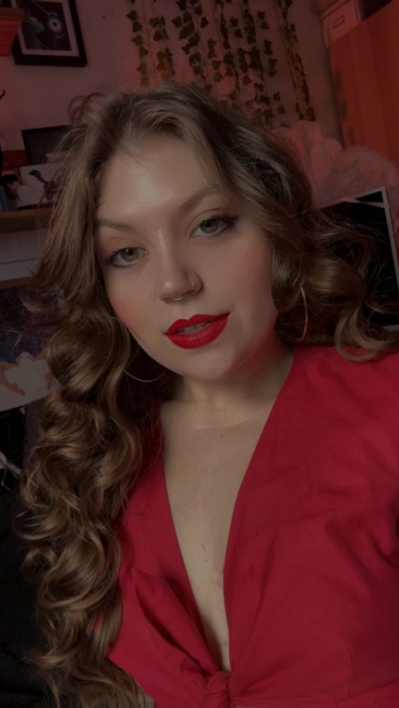 A photo of me in a red top and red lipstick. My curls are VERY curly today and once again hiding my elf ears. I hope you have a great day!