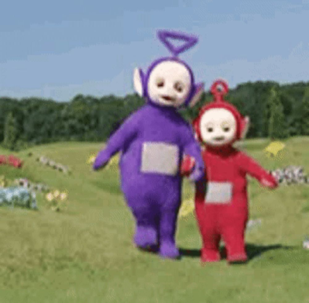 two teletubbies , purple and red , are walking in a grassy field .