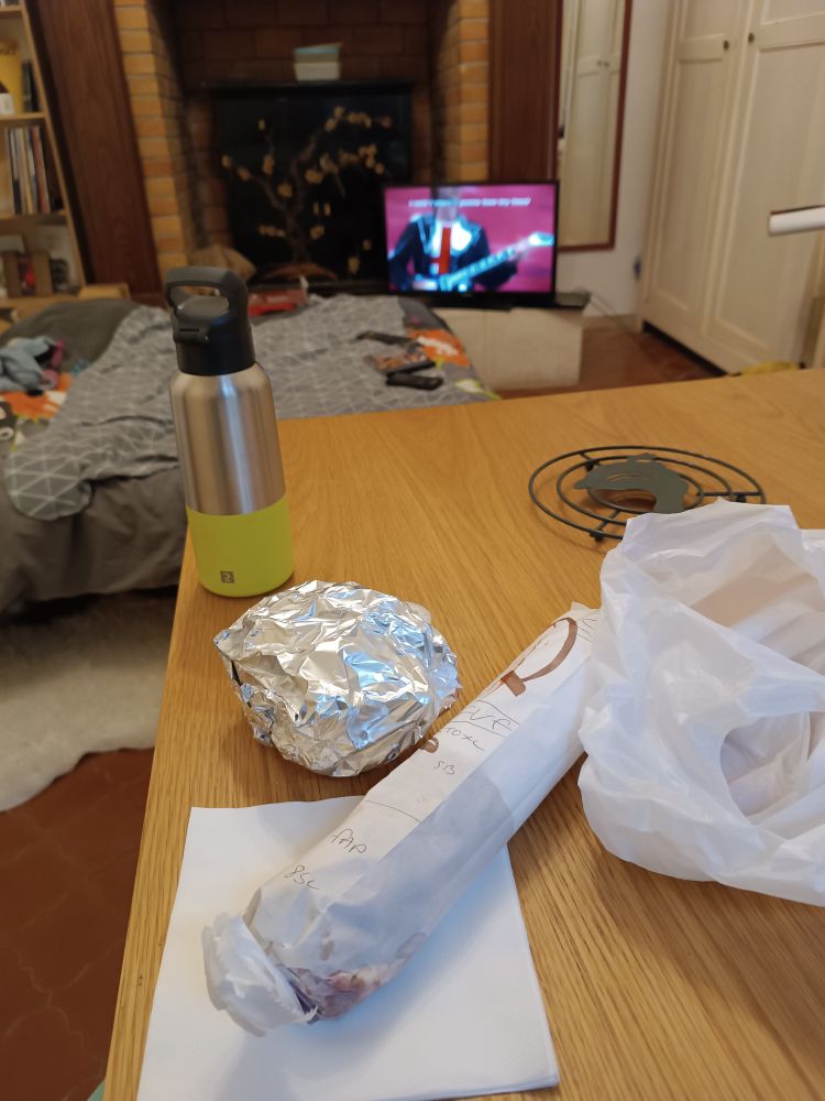 Nourriture emballée (frites et kebab vg) sur une table en bois devant music and lyrics