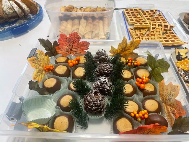 Kekse, Waffeln und Zigarrenbureks, dekoriert mit bunten Blättern und Zapfen auf einem Tisch 