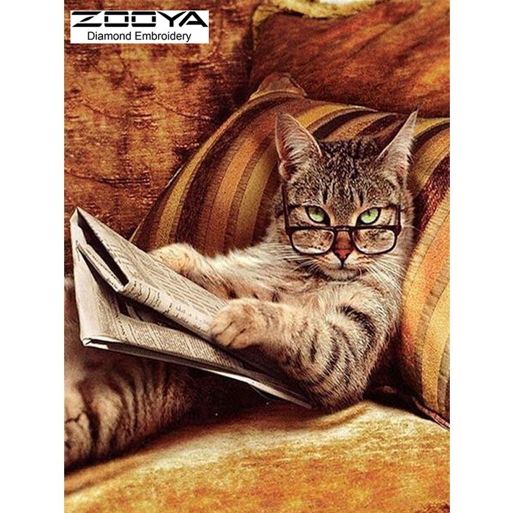 getigerte Katze liegt auf einem gold-brauen Sofa und hält eine Zeitung in den Pfoten. Auf der Nase trägt sie eine Brille über deren Rand sie die Betrachter:innen beobachtet.