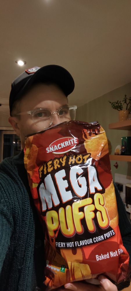 A greedy boy holds a massive bag of giant off-brand Wotsits
