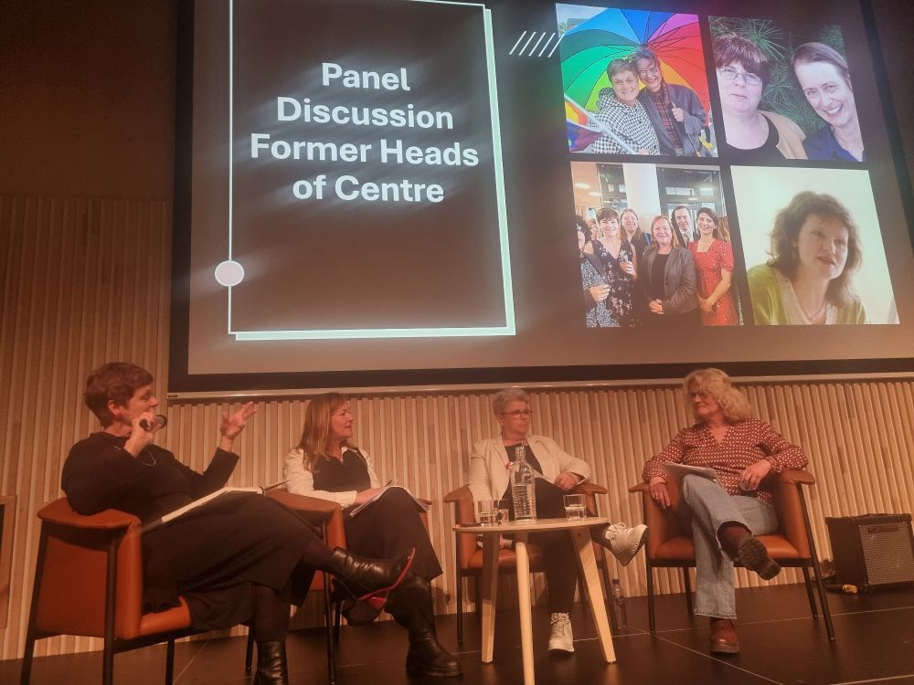 Four women in chairs in front of a table, a screen behind them with the text Panel Discussion Former Heads of Centre to the left, and images of all four women to the right 
