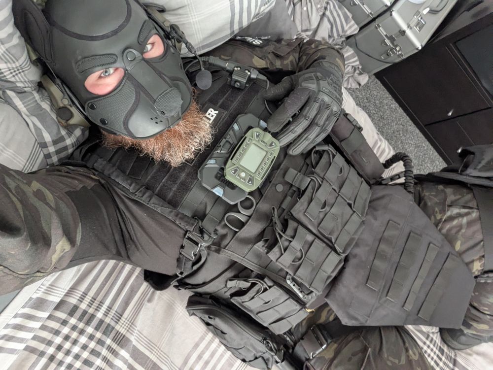 Human pup wearing military gear, laying down on a bed giving you come hither eyes
