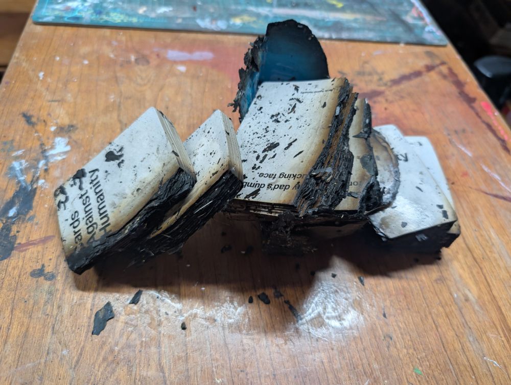 A wet, chunky stack of white cards. They're covered in ash and burned on one side. 