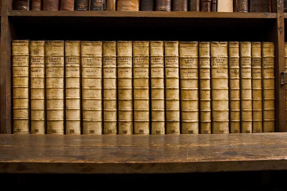 A bookshelf with a row of historic books, all bound in light brown leather