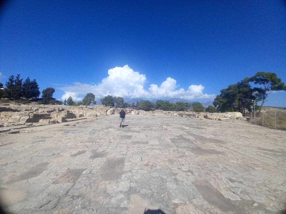 The central court, vast and flat and paved. A distant R for scale in black shirt and teal shorts is in the middle distance.