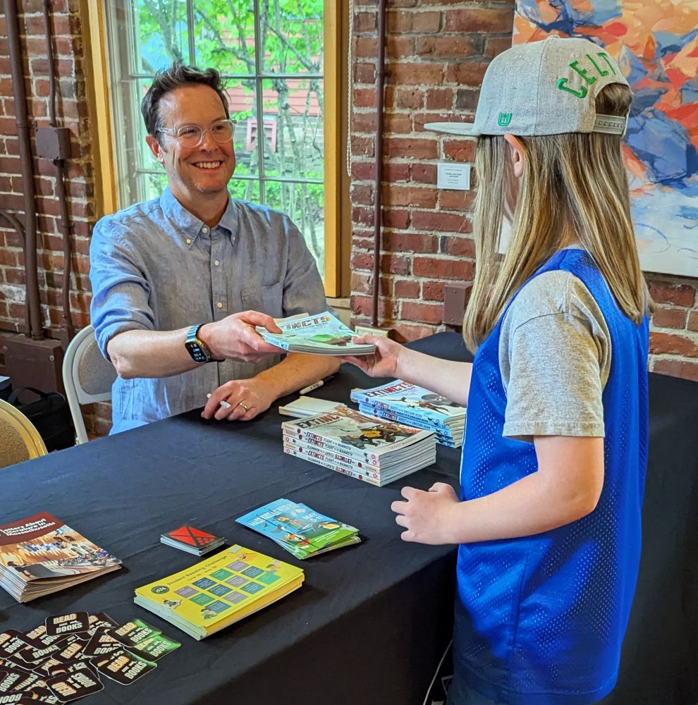 Scott hands book to young reader 